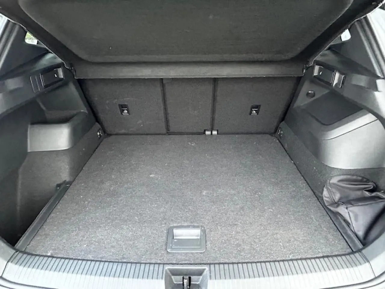 Coffre ouvert du Volkswagen Tiguan III gris clair, vue intérieure arrière montrant un espace de chargement spacieux.