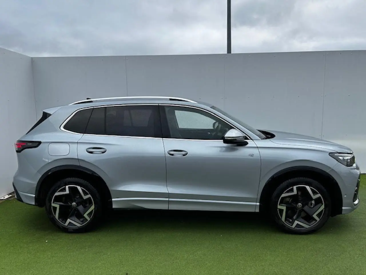 Volkswagen Tiguan III gris clair vu de profil côté gauche avec jantes alliage 19 pouces et vitres teintées.