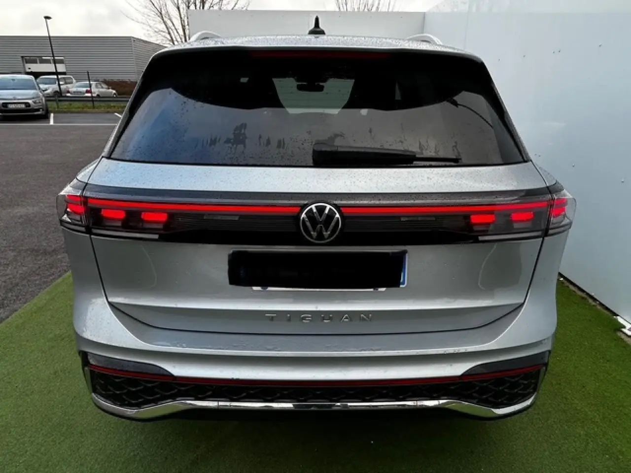 Vue arrière d'un Volkswagen Tiguan gris clair 2024 avec feux arrière LED reliés par une bande lumineuse rouge.