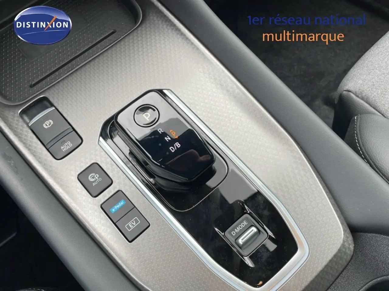 Vue rapprochée sur la console centrale du Nissan Qashqai gris, mettant en valeur le levier de vitesse automatique et les boutons de contrôle.