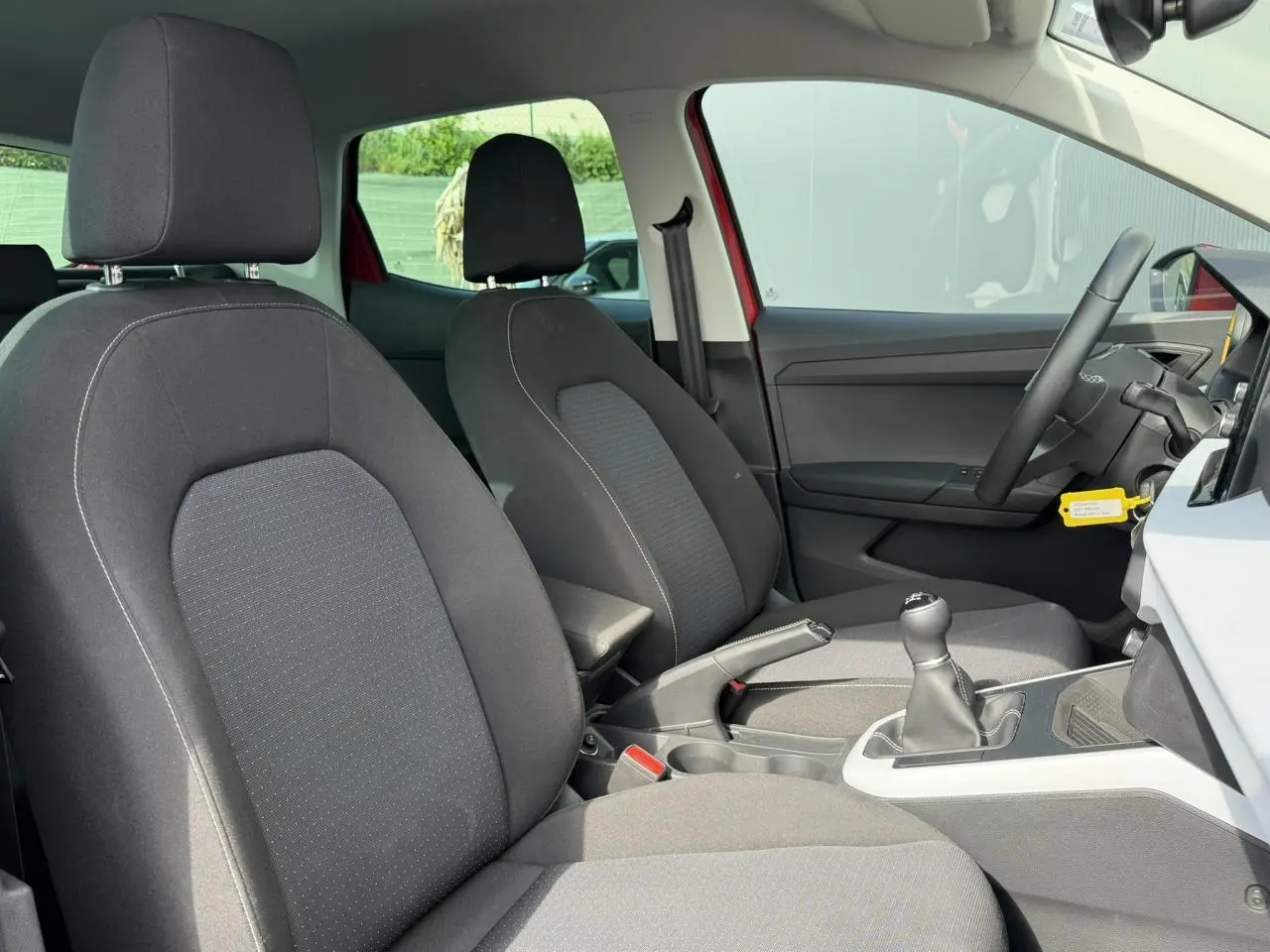 Intérieur avant du SEAT Arona rouge Désir 2025, vue côté droit montrant les sièges noirs et la boîte manuelle.