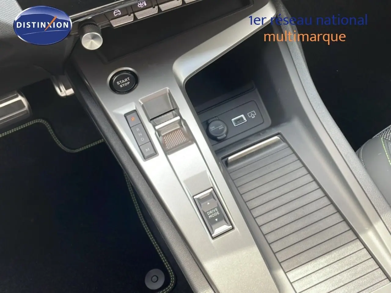 Vue rapprochée de la console centrale grise avec bouton start/stop et commande de boîte auto sur Peugeot 308 hybride 2026.