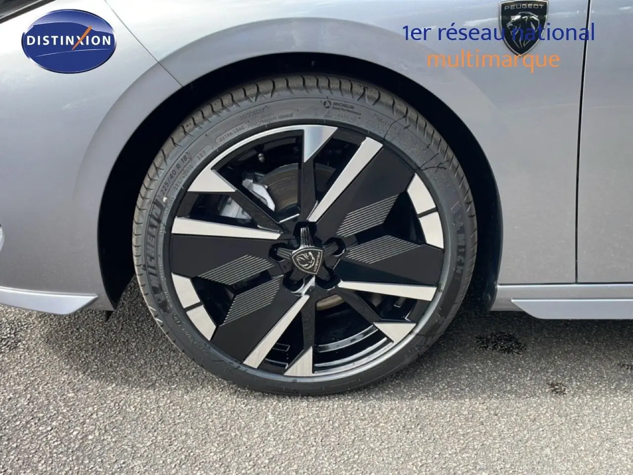Gros plan sur la roue avant droite d’une Peugeot 308 gris Artense métal, avec jante noire et argentée au design moderne.