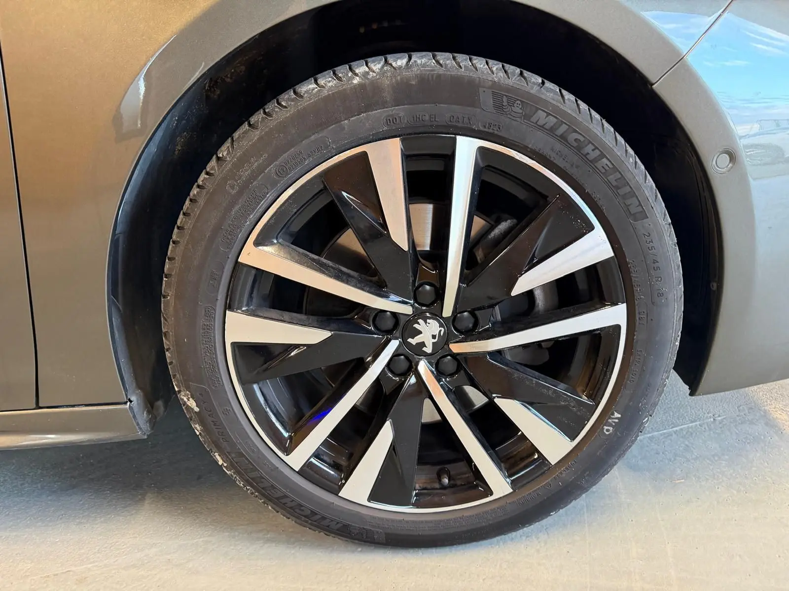 Gros plan sur la jante alu noire et argentée d'une Peugeot 508 gris, avec logo lion au centre.