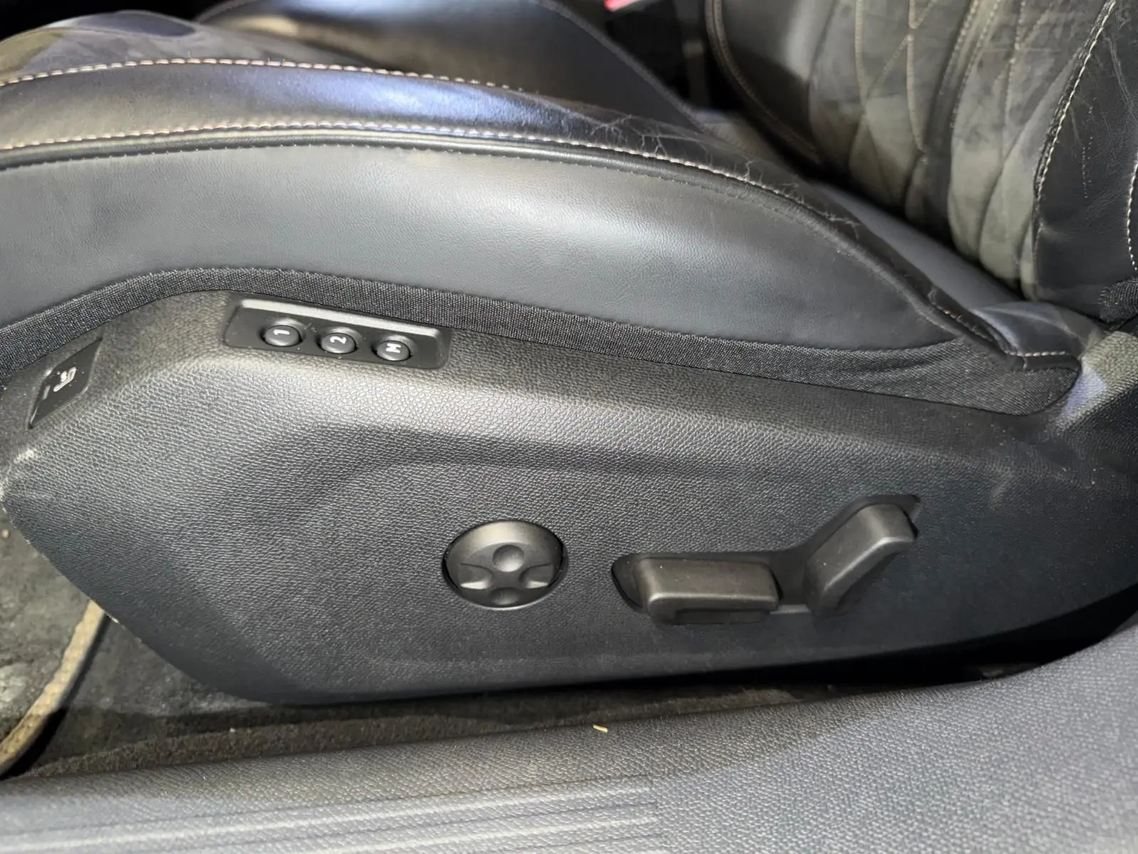 Détail des commandes de réglage électrique du siège avant en cuir noir de la Peugeot 508 gris, vue latérale.