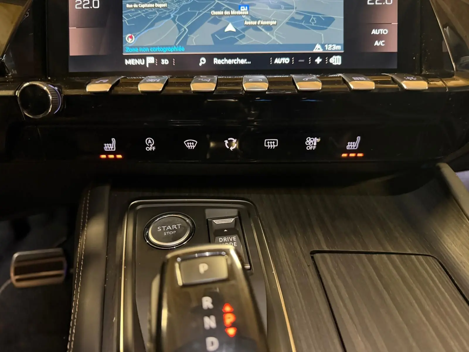 Vue rapprochée de la console centrale en bois gris avec levier de vitesses, boutons chauffants et écran tactile du Peugeot 508 gris.