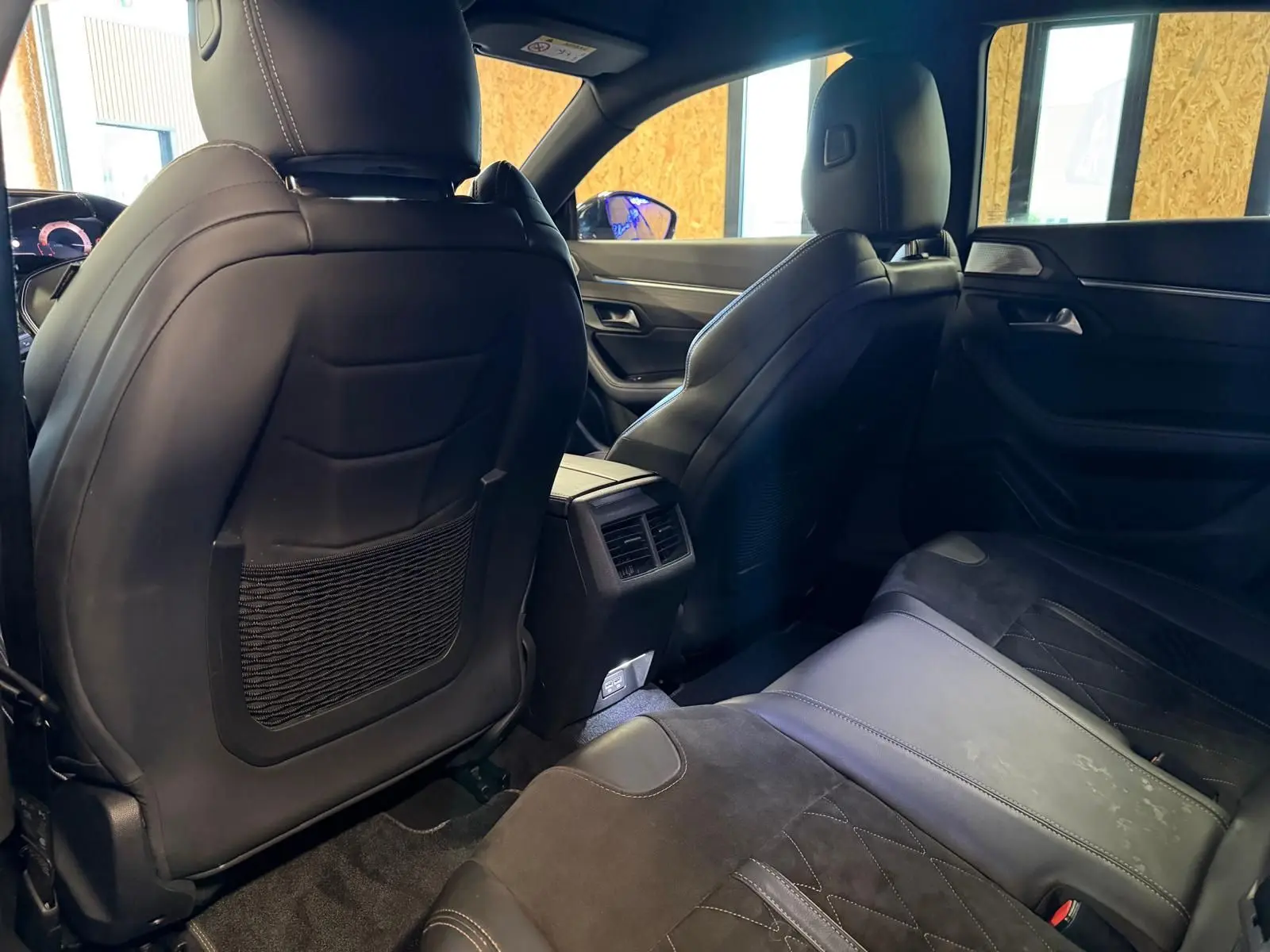 Vue intérieure arrière montrant les sièges en cuir noir et Alcantara gris du Peugeot 508 gris, avec prises USB et accoudoir central.