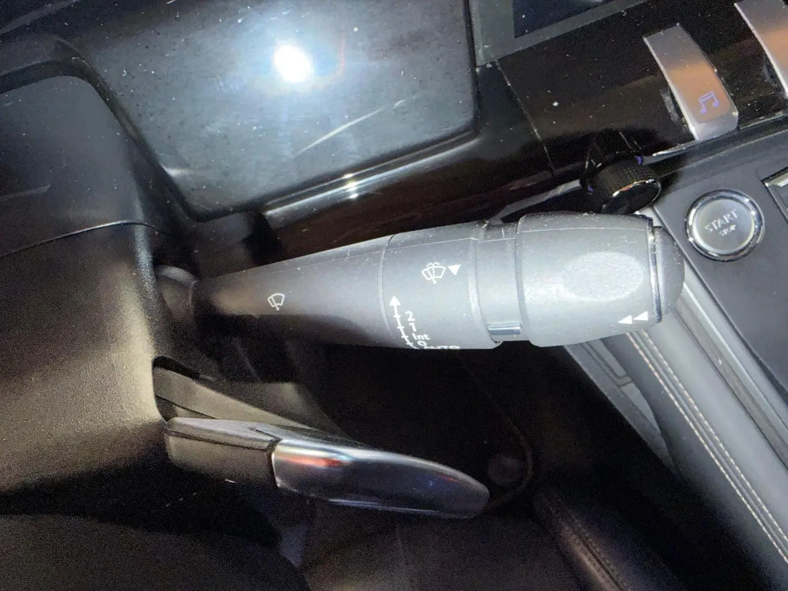 Gros plan sur la commande d’essuie-glace et le bouton start/stop dans l’habitacle noir de la Peugeot 508 gris 2019.