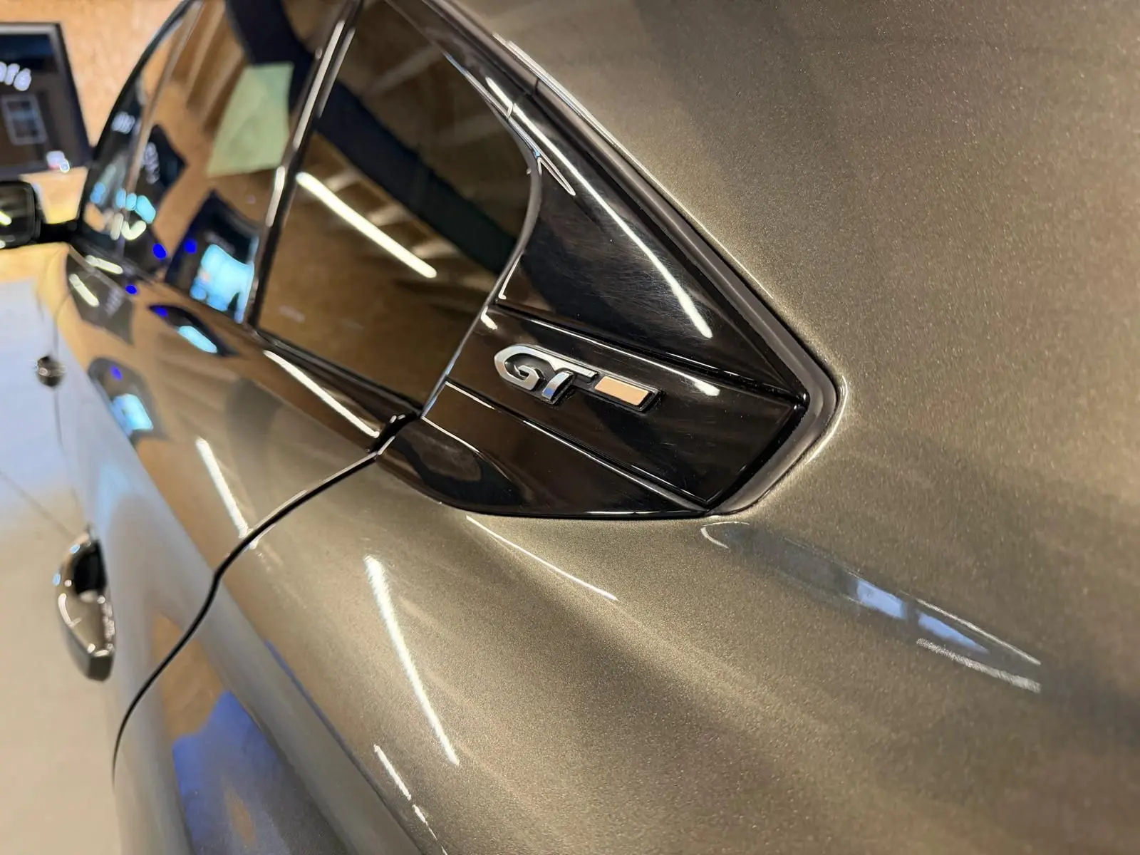 Détail du logo GT sur la custode côté droit d’une Peugeot 508 gris métallisé en intérieur.