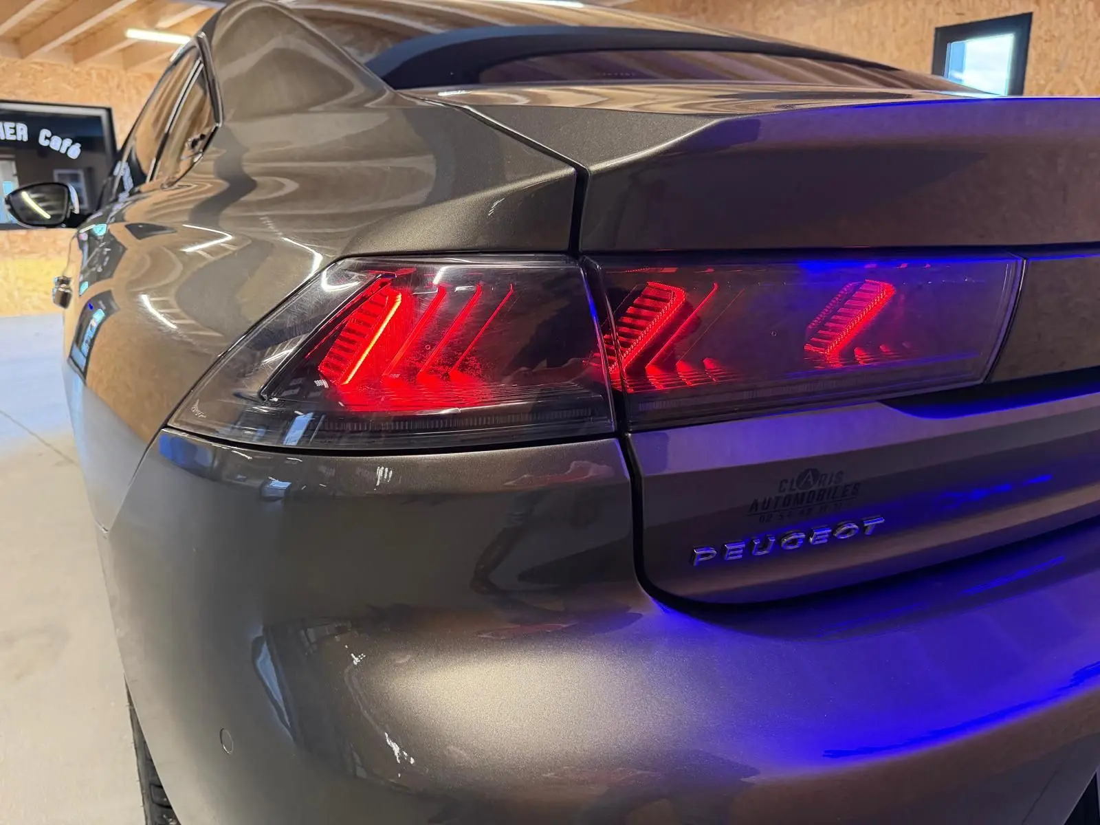 Vue 3/4 arrière gauche d'une Peugeot 508 gris métallisé avec feux arrière LED allumés en intérieur.