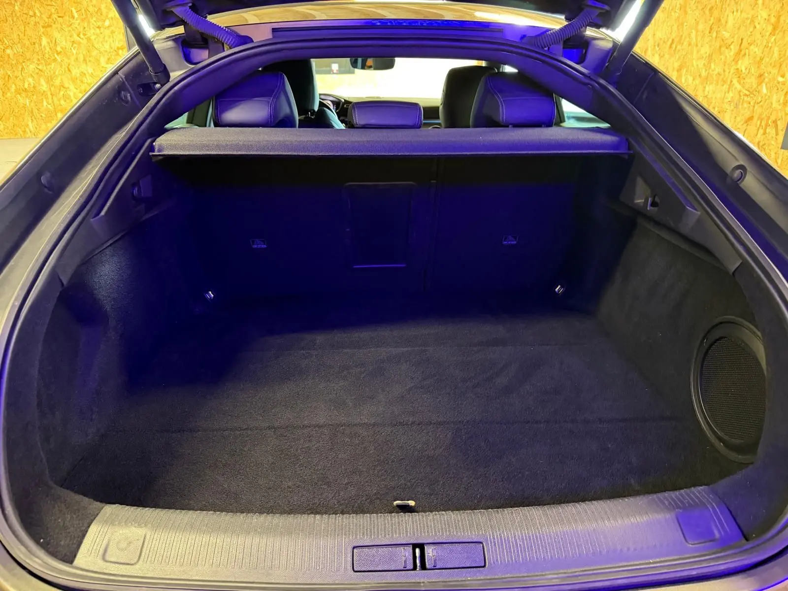 Vue intérieure du coffre ouvert de la Peugeot 508 gris, montrant un espace de rangement propre et un haut-parleur latéral.