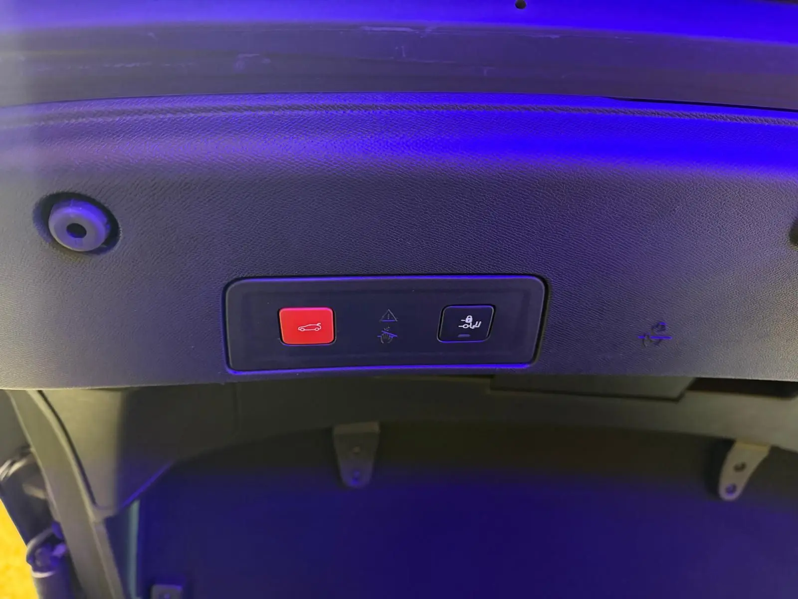Gros plan sur les boutons de fermeture et de verrouillage du hayon d'une Peugeot 508 gris, éclairage bleu.