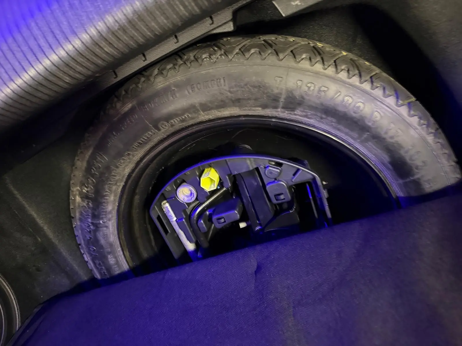 Gros plan sur la roue de secours et les outils de bord dans le coffre d'une Peugeot 508 gris 2019.