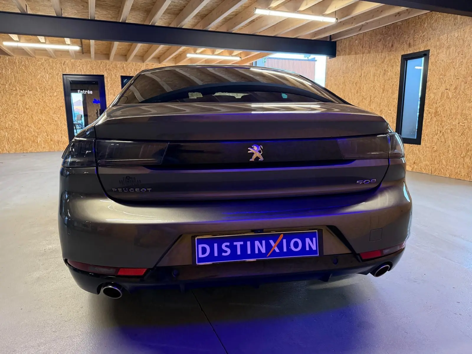 Vue arrière d'une Peugeot 508 gris métallisé avec feux arrière noirs et double sortie d'échappement en intérieur.