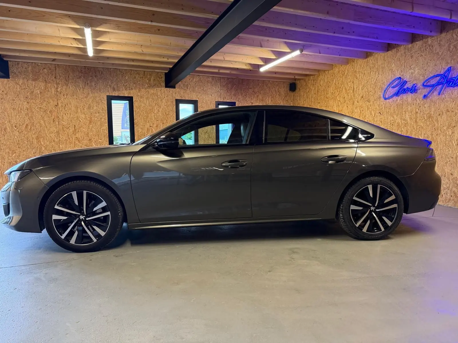 Peugeot 508 gris en profil droit dans un intérieur, avec jantes alliage noires et vitres teintées.