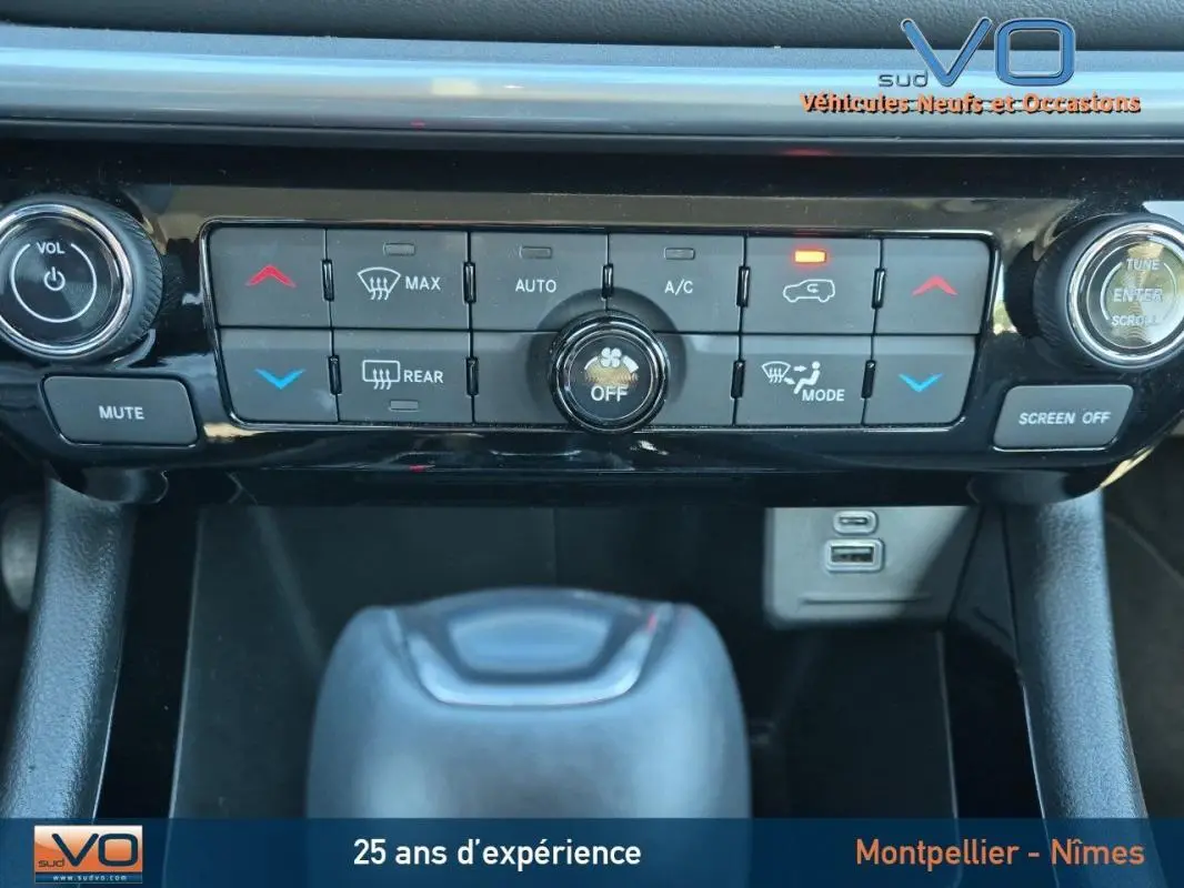 Vue rapprochée de la console centrale du Jeep Compass gris 2024, mettant en valeur les commandes de climatisation et la prise USB.
