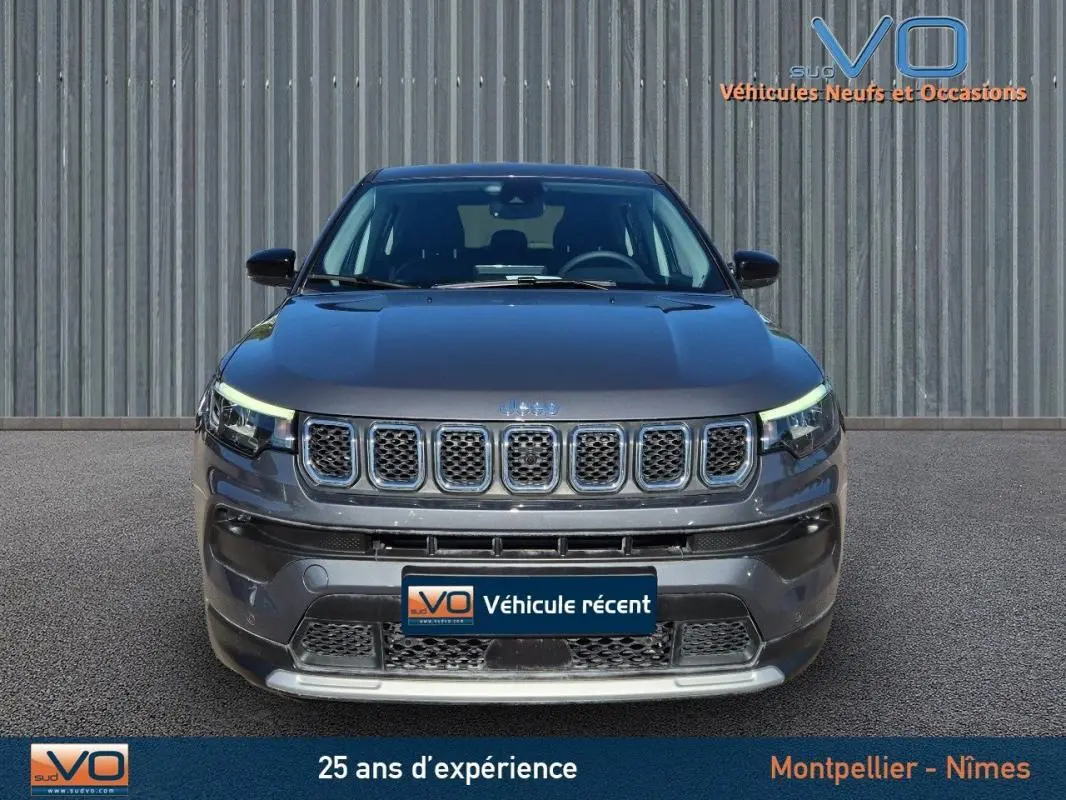 Vue avant d'un Jeep Compass gris 2024 avec calandre distinctive et phares LED allumés.