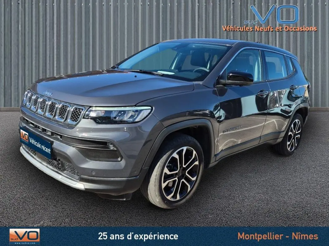 Jeep Compass gris vue 3/4 avant droit, jantes alliage 18 pouces, calandre distinctive et phares LED visibles.