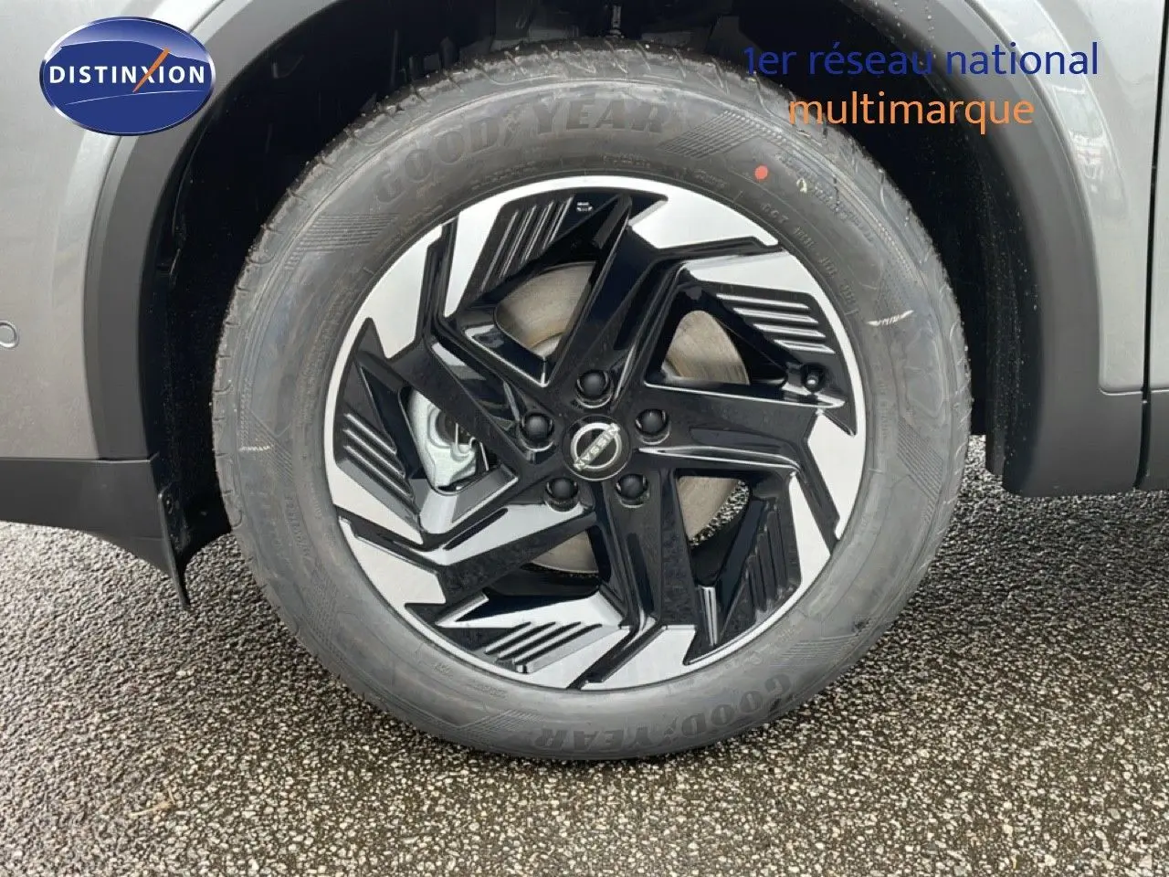 Gros plan sur la roue avant droite du Nissan Qashqai gris squale métal, jante noire et argentée au design moderne.