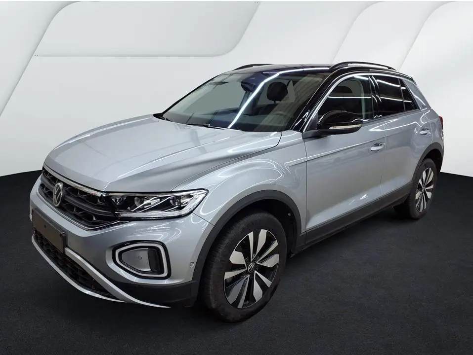 Volkswagen T-Roc gris clair vue 3/4 avant droit, toit noir brillant et jantes alliage distinctives.