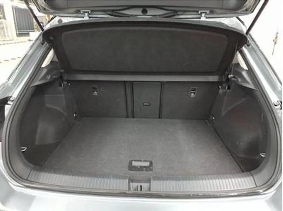 Coffre ouvert vu de l'arrière d'un Volkswagen T-Roc gris clair 2025, espace de chargement vide et propre.