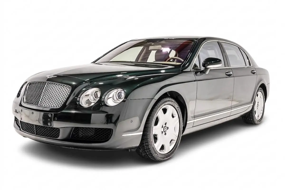 Vue 3/4 avant droite d'une Bentley Continental Flying Spur vert foncé avec calandre chromée et jantes blanches.