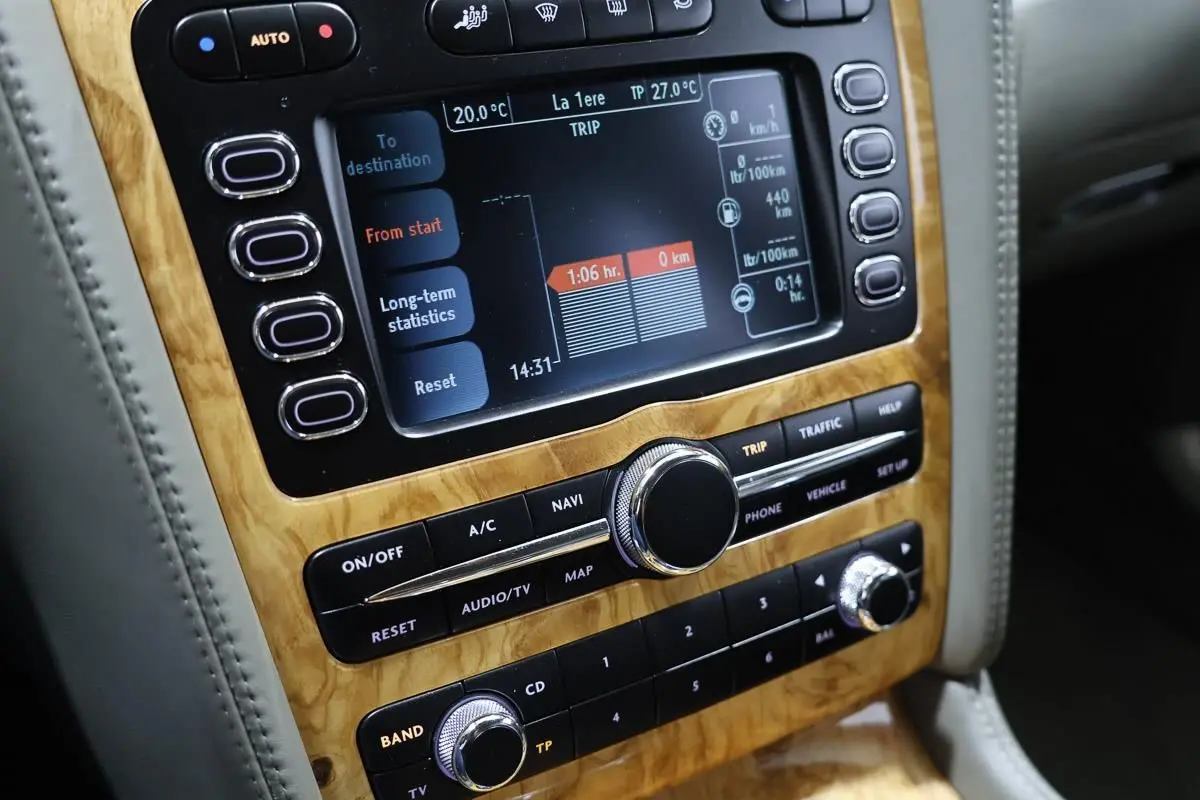 Gros plan sur la console centrale en bois clair de la Bentley Continental Flying Spur 2006, affichage numérique et commandes audio.