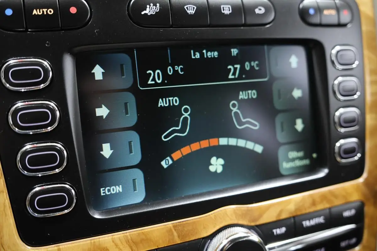Écran tactile de la climatisation automatique sur tableau de bord en bois clair d’une Bentley Continental Flying Spur.