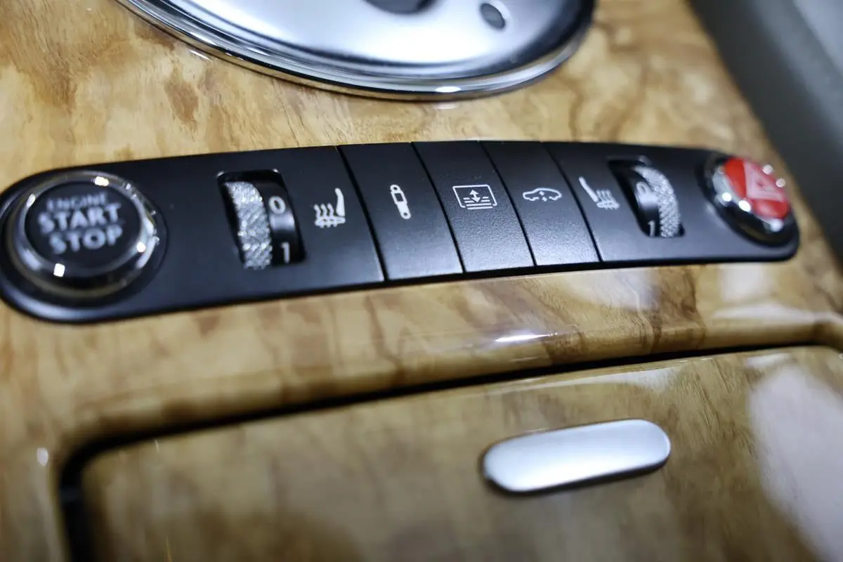 Gros plan sur la console en bois clair de la Bentley Continental Flying Spur 2006, montrant les boutons de démarrage et réglages sièges.
