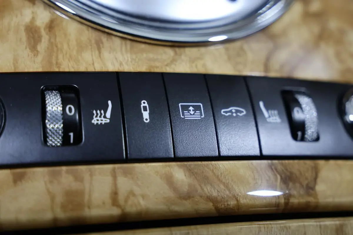 Gros plan sur les commandes de réglage des sièges chauffants et suspension sur bois clair intérieur d’une Bentley Continental Flying Spur 2006.