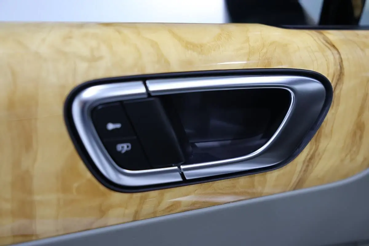 Poignée de porte intérieure en métal brossé sur garniture bois clair d’une Bentley Continental Flying Spur 2006.
