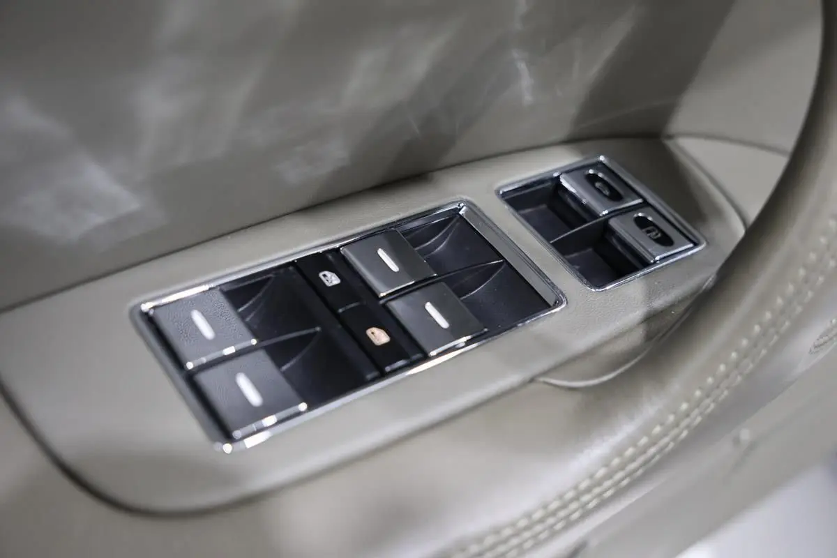 Gros plan sur les commandes de lève-vitres chromées intégrées dans la porte beige du Bentley Continental Flying Spur.