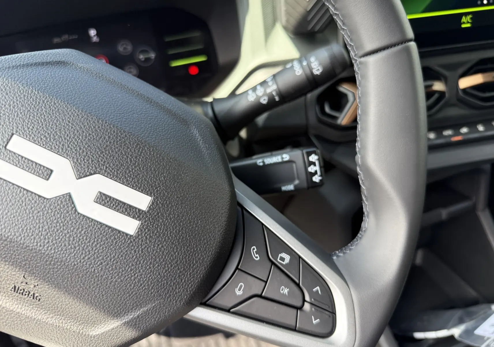 Gros plan sur le volant gris du Dacia Duster Hybrid 155 Extreme 2026, avec commandes intégrées et tableau de bord partiellement visible.