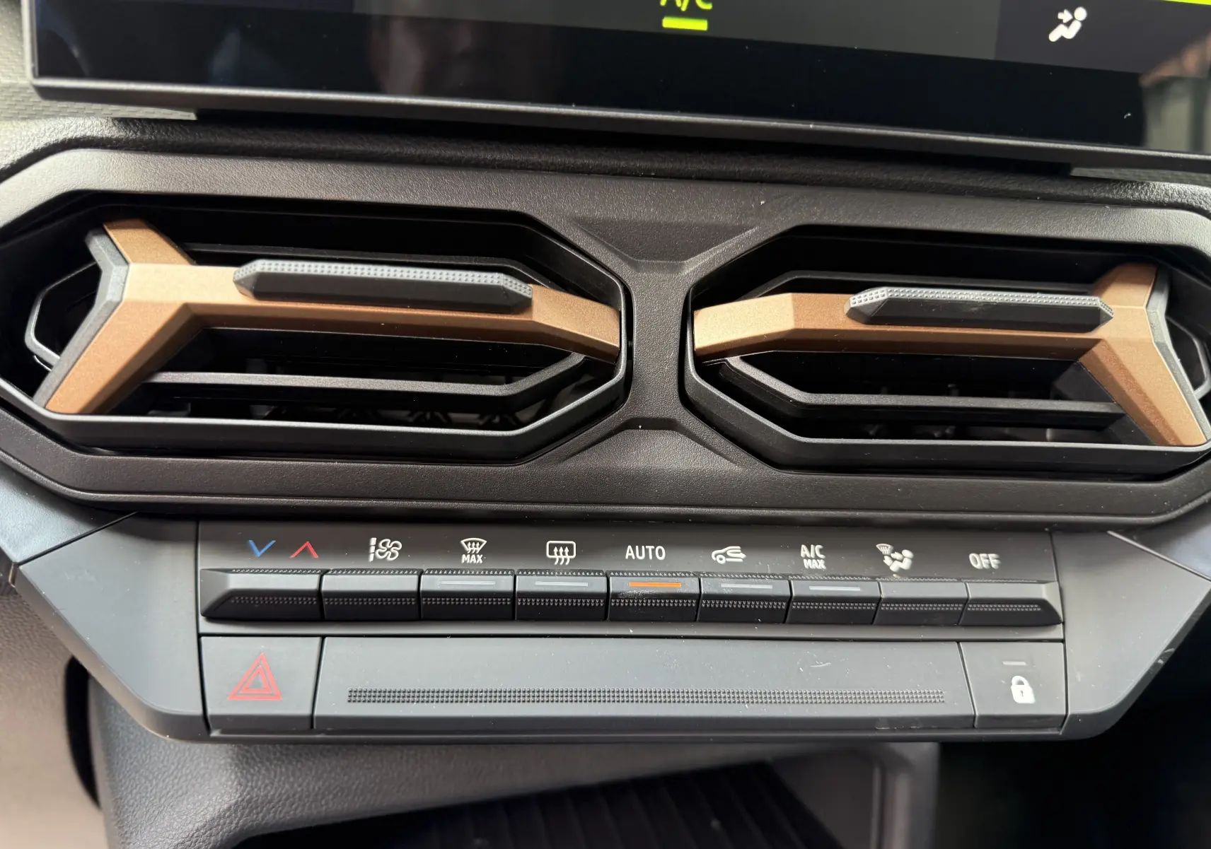 Gros plan sur les aérateurs et commandes de climatisation du tableau de bord du Dacia Duster Hybrid 155 Extreme blanc glacier 2026.