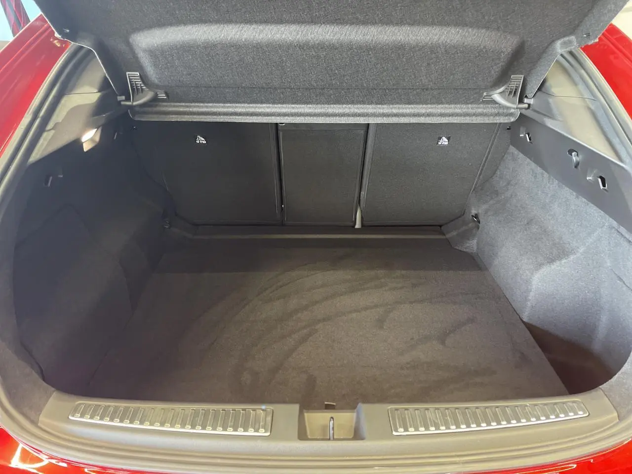 Coffre ouvert vu de l'arrière d'une Renault Rafale rouge avec intérieur noir et banquette rabattue partiellement.