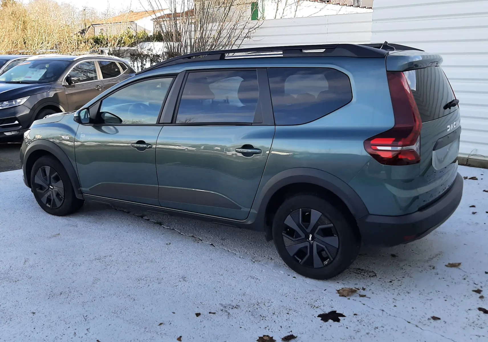 Vue de profil côté gauche d'un Dacia Jogger 2025 vert cèdre métallisé avec toit noir et jantes noires.