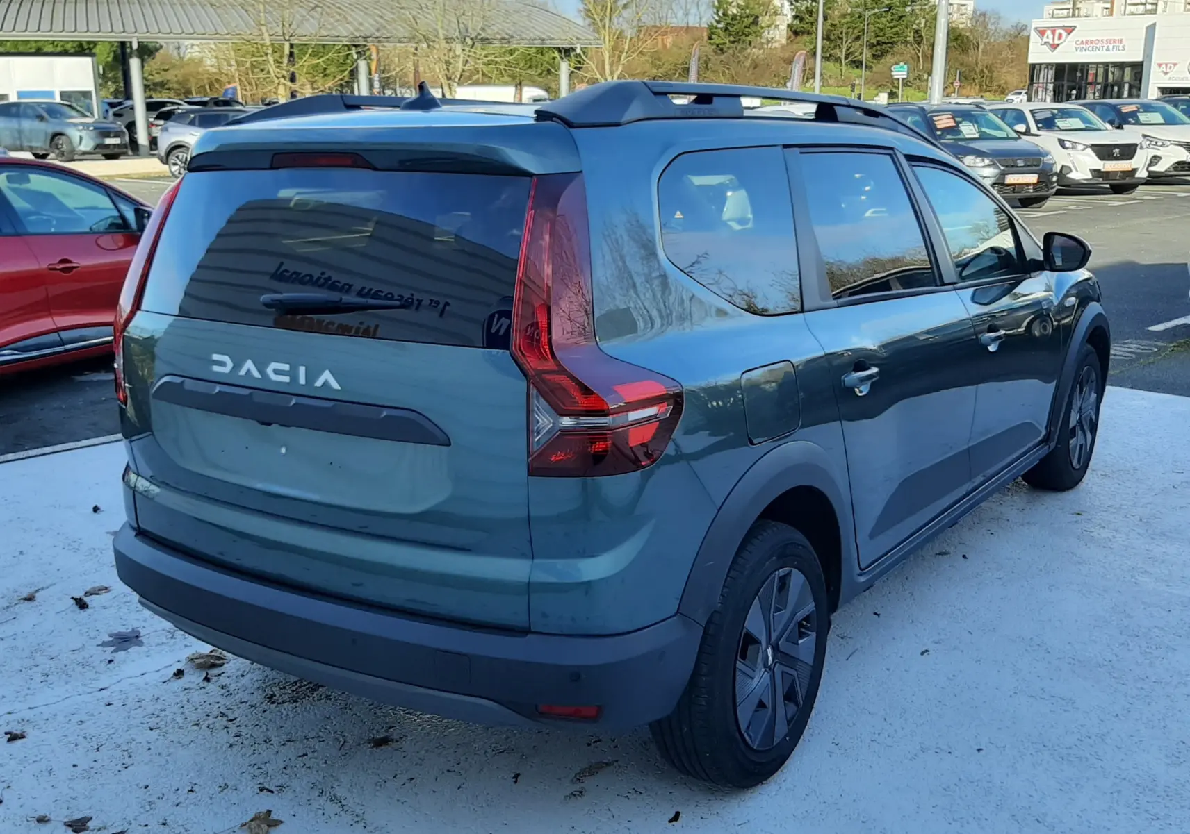Vue 3/4 arrière droite d'un Dacia Jogger vert cèdre métal 2025 avec toit noir et vitres teintées.