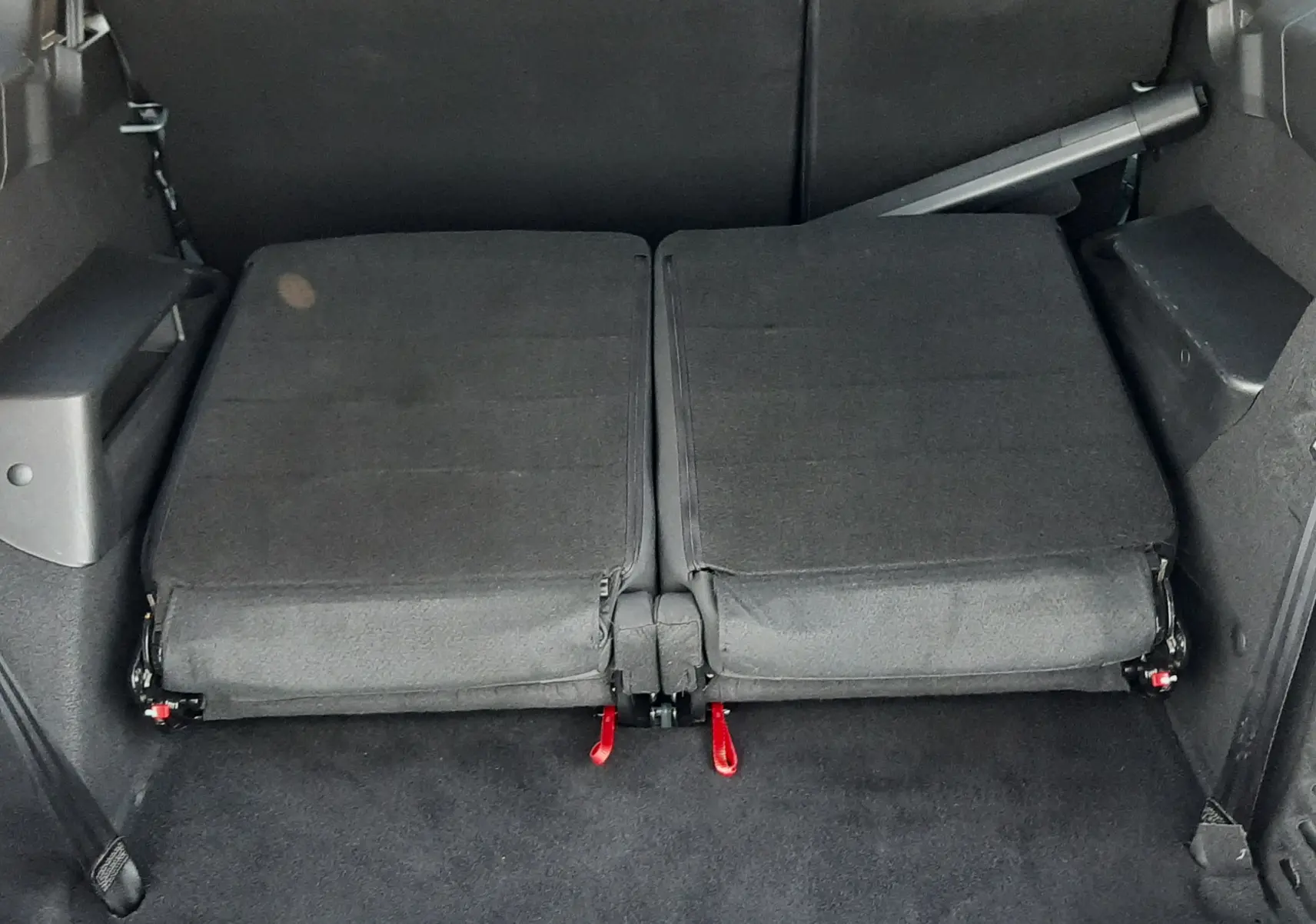 Vue arrière du coffre du Dacia Jogger 2025 avec sièges rabattus en tissu noir, offrant un espace de chargement plat.