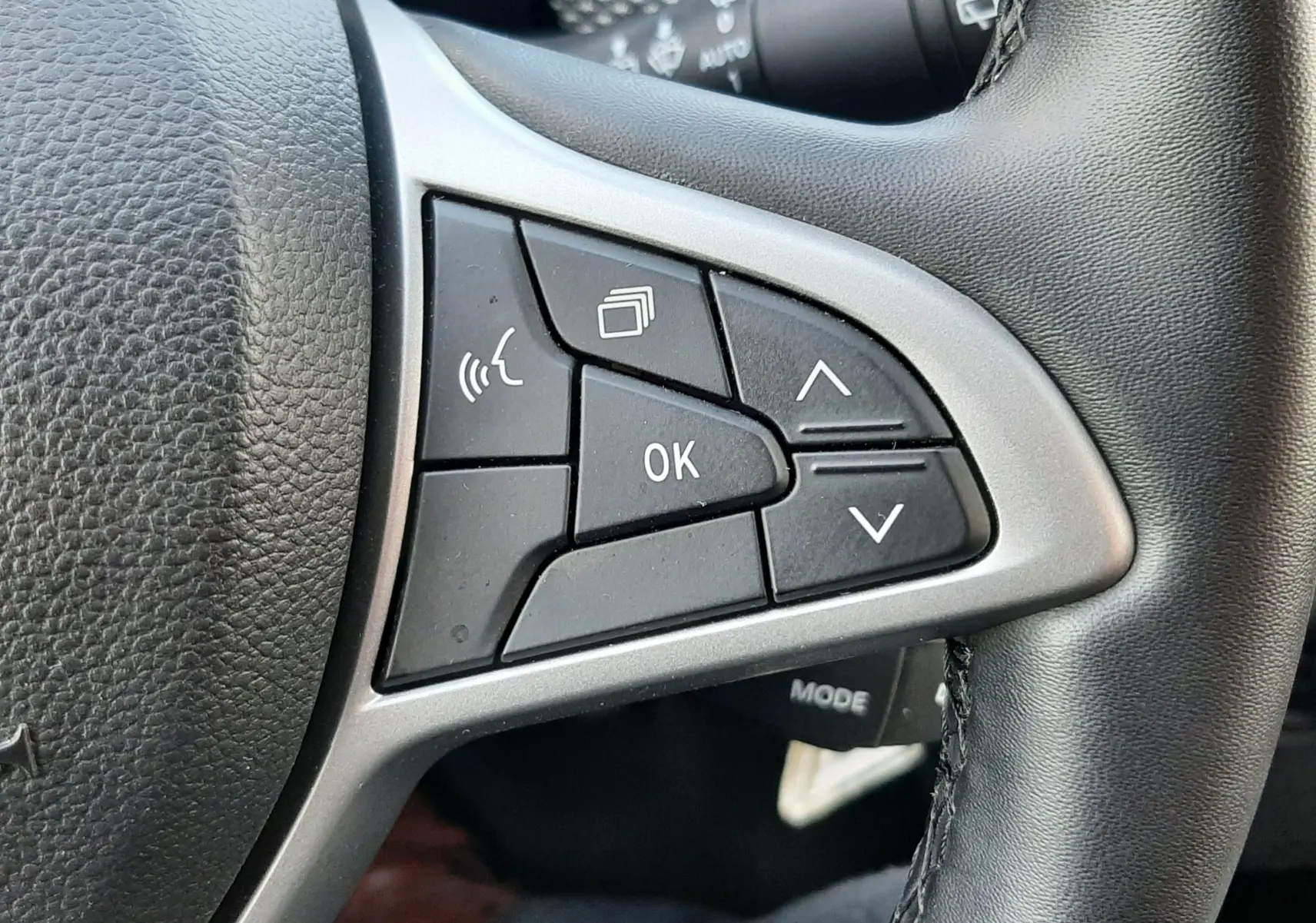 Gros plan sur les commandes multifonctions à gauche du volant en cuir noir du Dacia Jogger 2025.