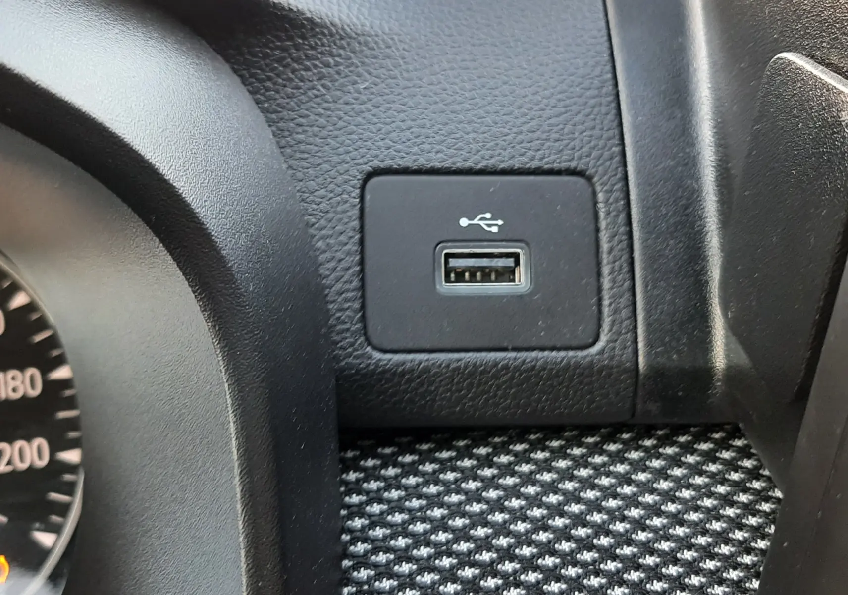 Vue rapprochée du port USB intégré sur la console noire texturée du tableau de bord du Dacia Jogger 2025.