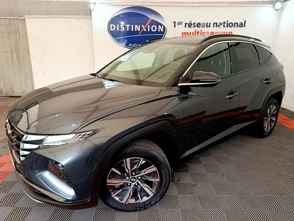 Vue 3/4 avant droit du Hyundai Tucson 1.6 Hybrid 230 Creative gris foncé, avec jantes alliage et vitres teintées.