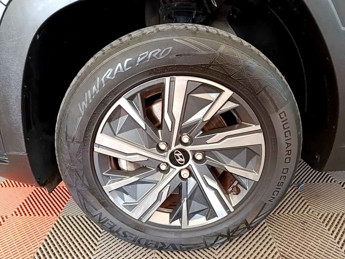 Gros plan sur la roue avant droite du Hyundai Tucson gris foncé, avec jante alu au design géométrique moderne.