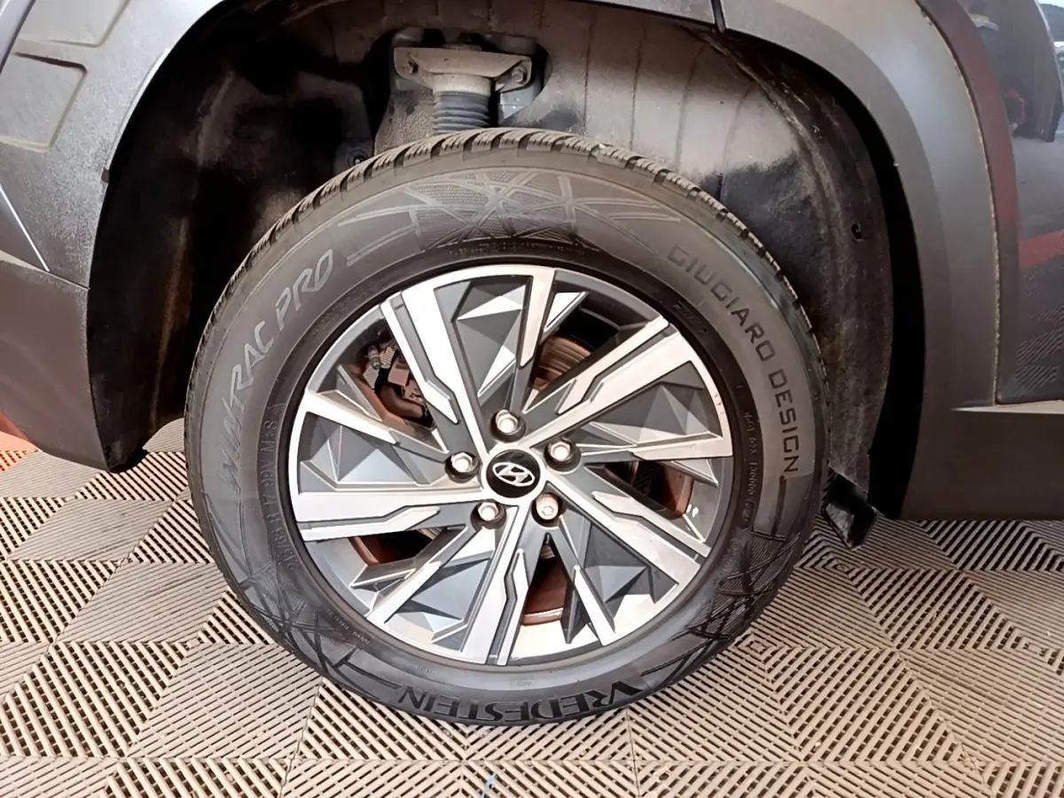 Gros plan sur la roue avant droite gris foncé du Hyundai Tucson 1.6 Hybrid 230 Creative avec jante alu au design géométrique.