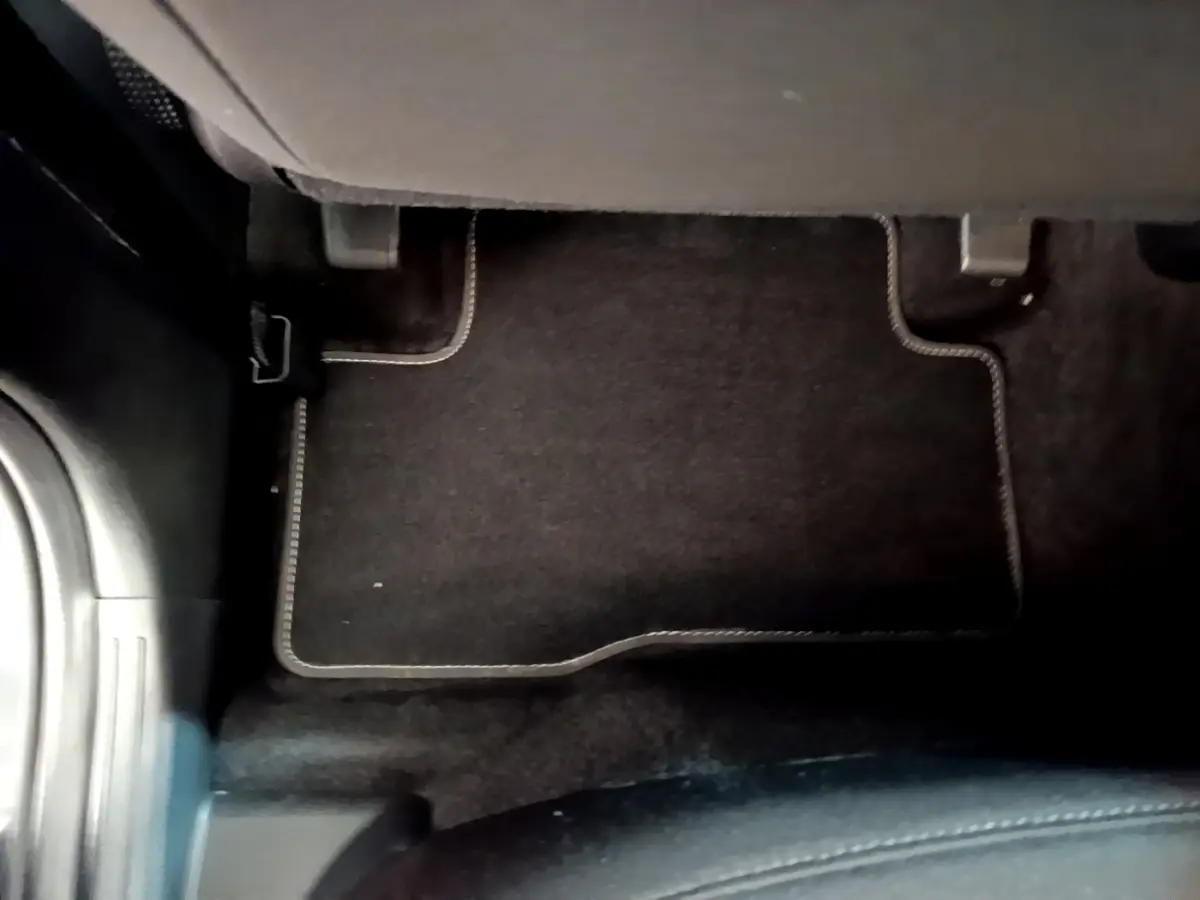 Vue rapprochée du tapis de sol noir avec surpiqûres blanches côté passager arrière d’un Hyundai Tucson gris foncé.