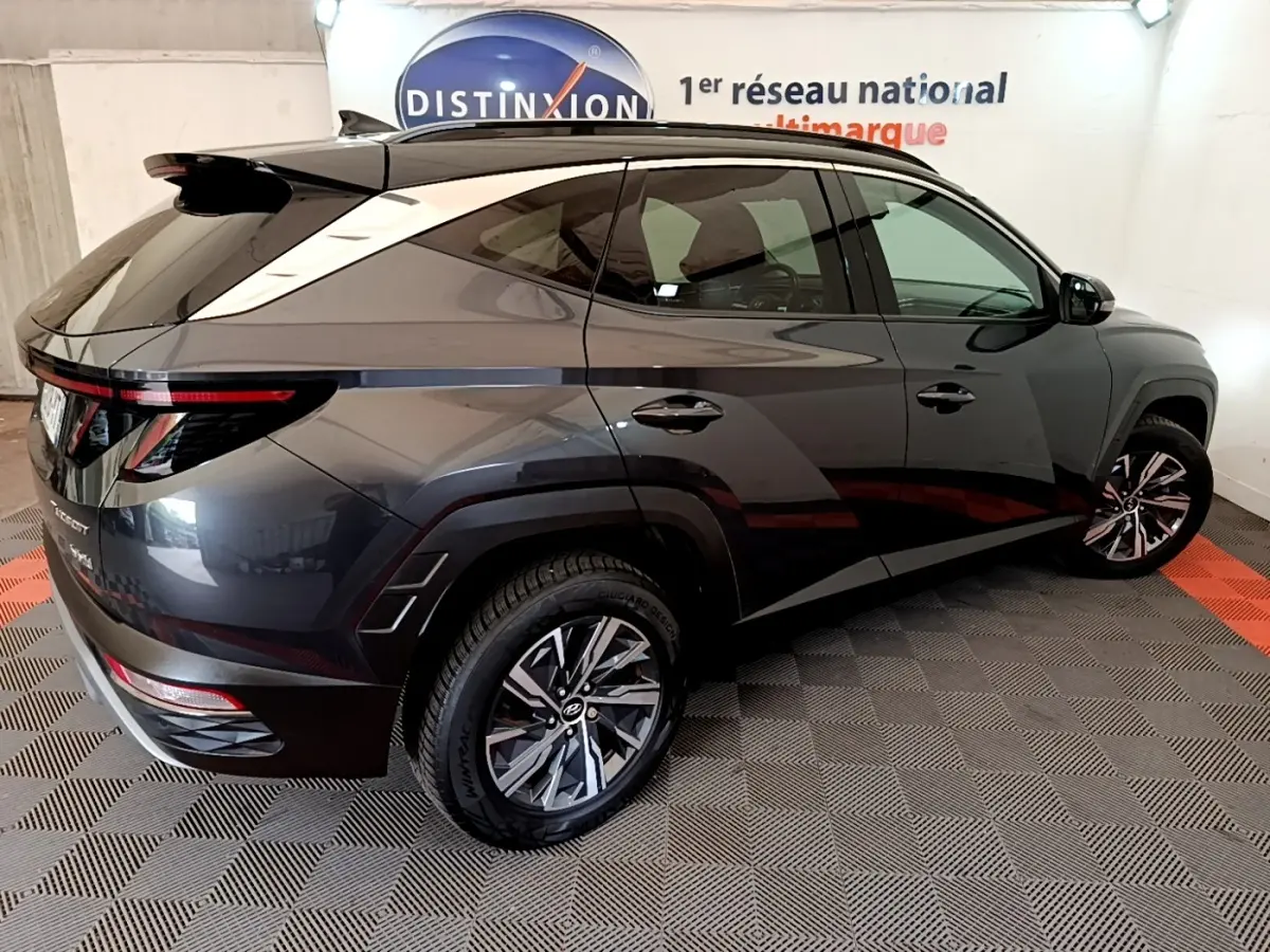Vue 3/4 arrière droite d’un Hyundai Tucson gris foncé 2022 avec jantes alliage et toit noir contrasté.