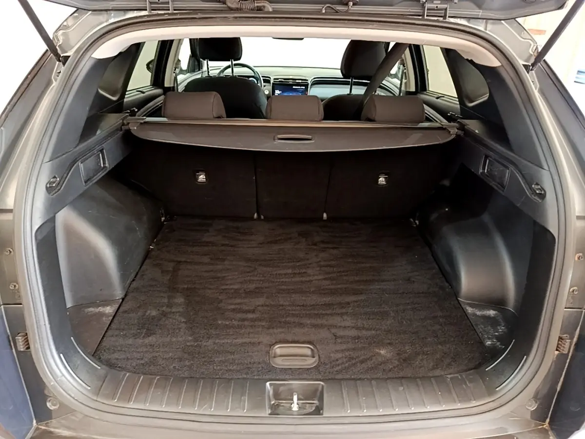 Coffre ouvert d’un Hyundai Tucson gris foncé, vue arrière montrant l’espace de chargement et la tablette cache-bagages.