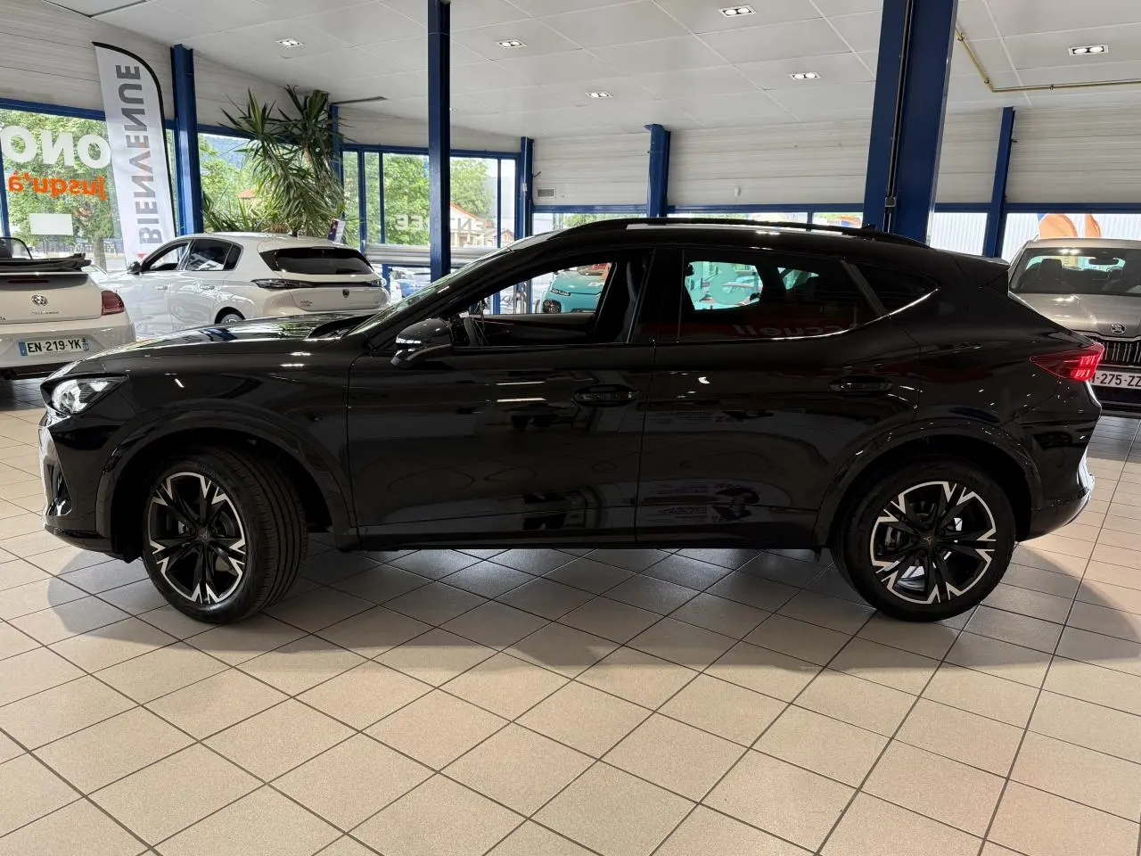 Vue de profil côté gauche d'une CUPRA Formentor 2025 noire Night avec jantes alliage 18'' en showroom.