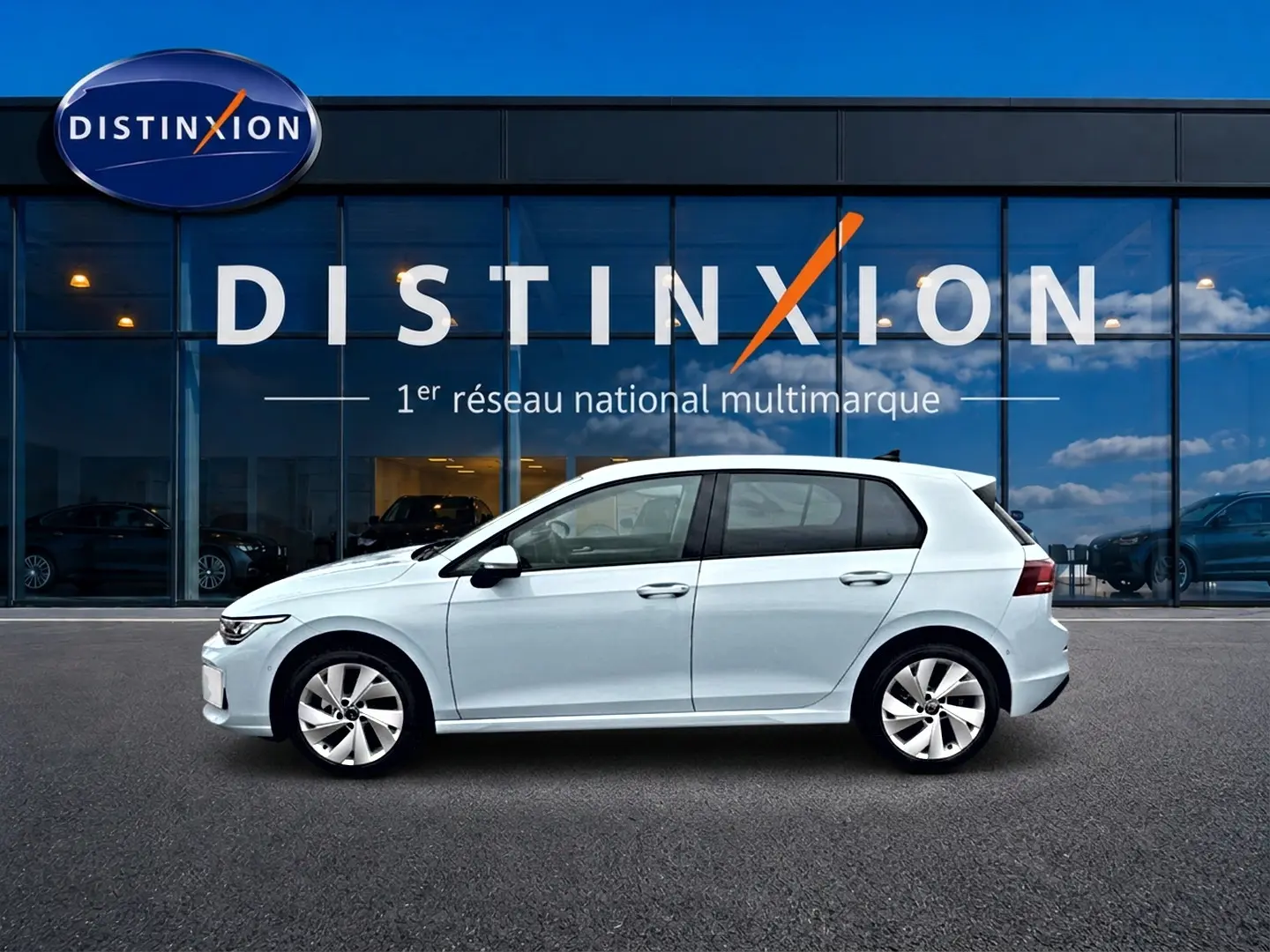 Vue de profil côté gauche d'une Volkswagen Golf 1.5 etsi evo2 116 life dsg7 bleu glacier devant une vitrine Distinxion.