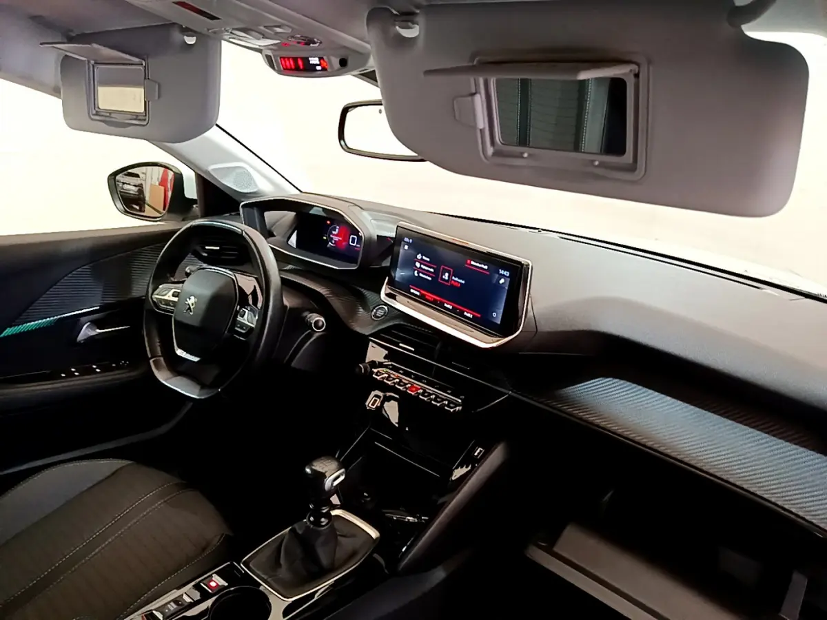 Intérieur noir de la Peugeot 208 PureTech 100, vue côté conducteur sur tableau de bord et écran tactile central.