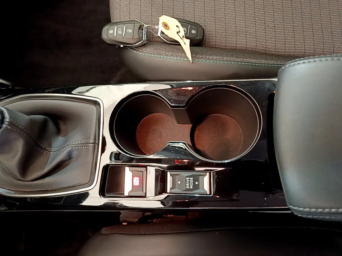Vue plongeante sur la console centrale noire du Peugeot 208 blanc, avec levier de vitesse manuel et porte-gobelets doubles.